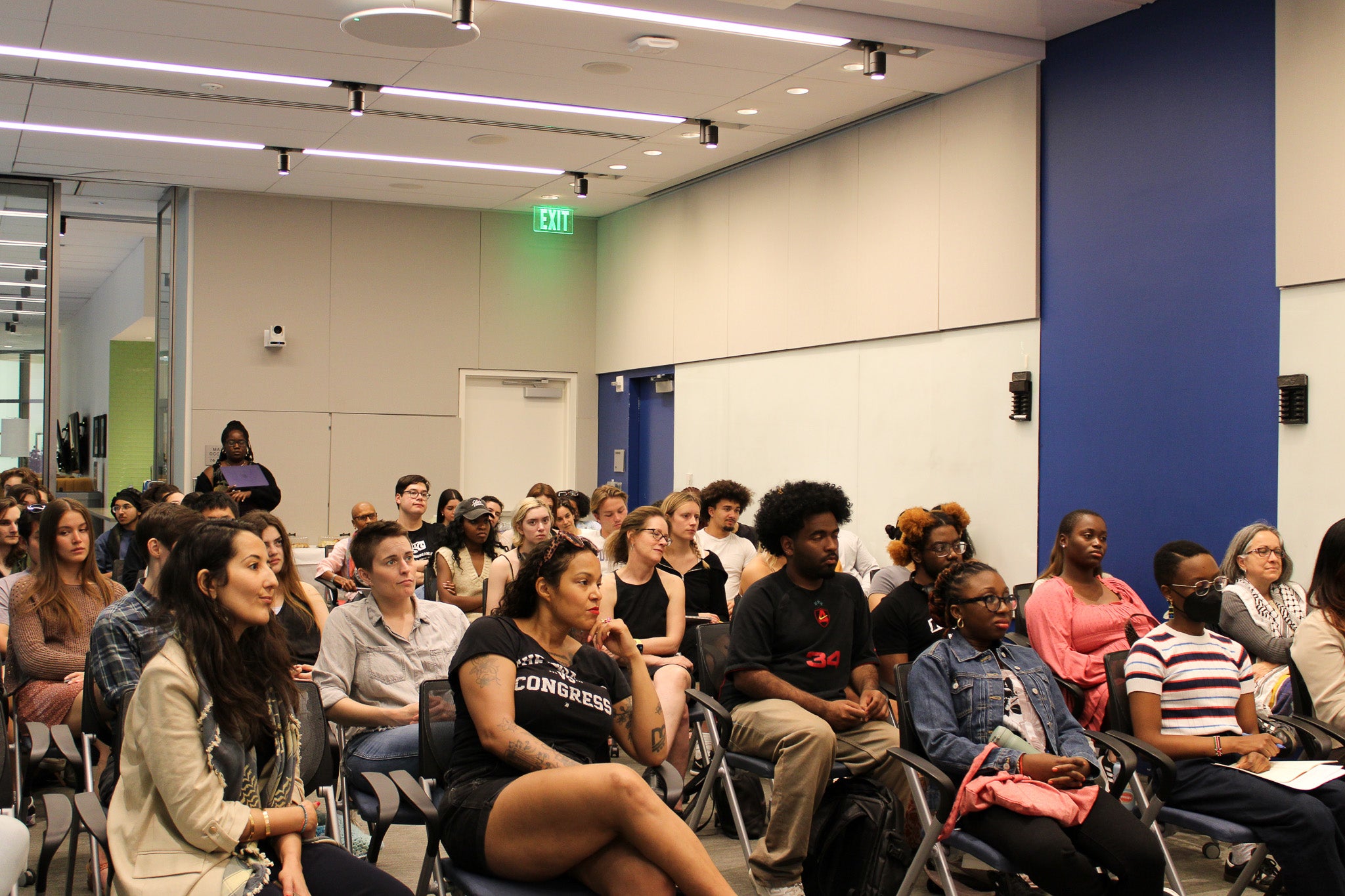 An audience full of racially and gender diverse people attentively listen to Dr. McFadden's lecture.