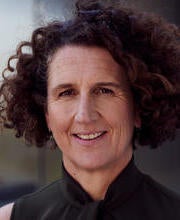 A woman with curly, short hair smiling.