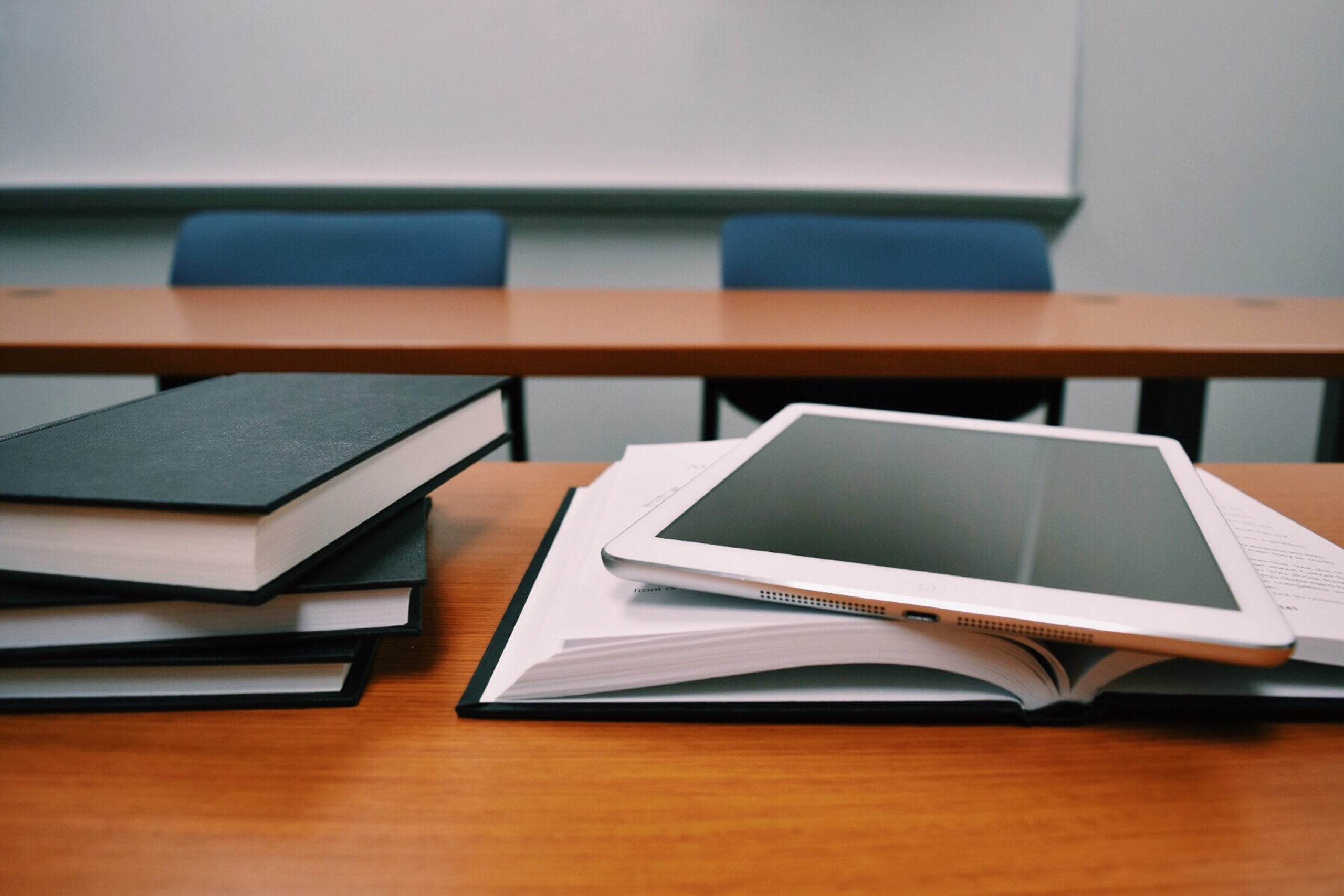 A bile of books and a tablet on a table.