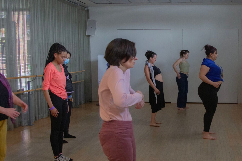 Several of the dancers of various ethnicities are stretching.