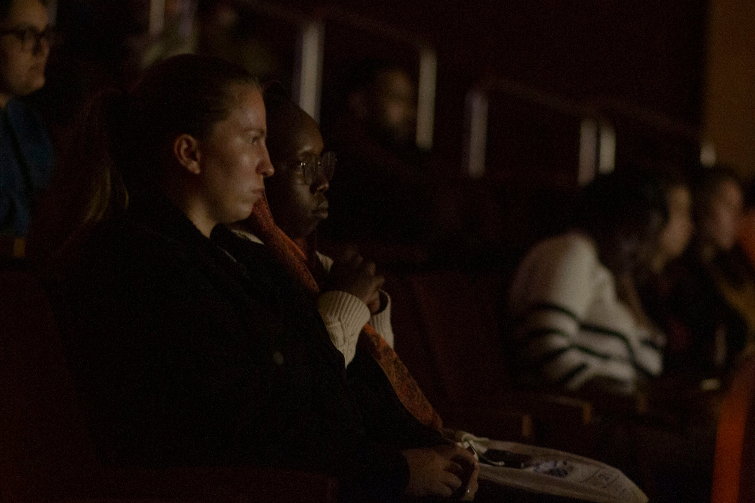 Audience members in a dark room, watching the film.