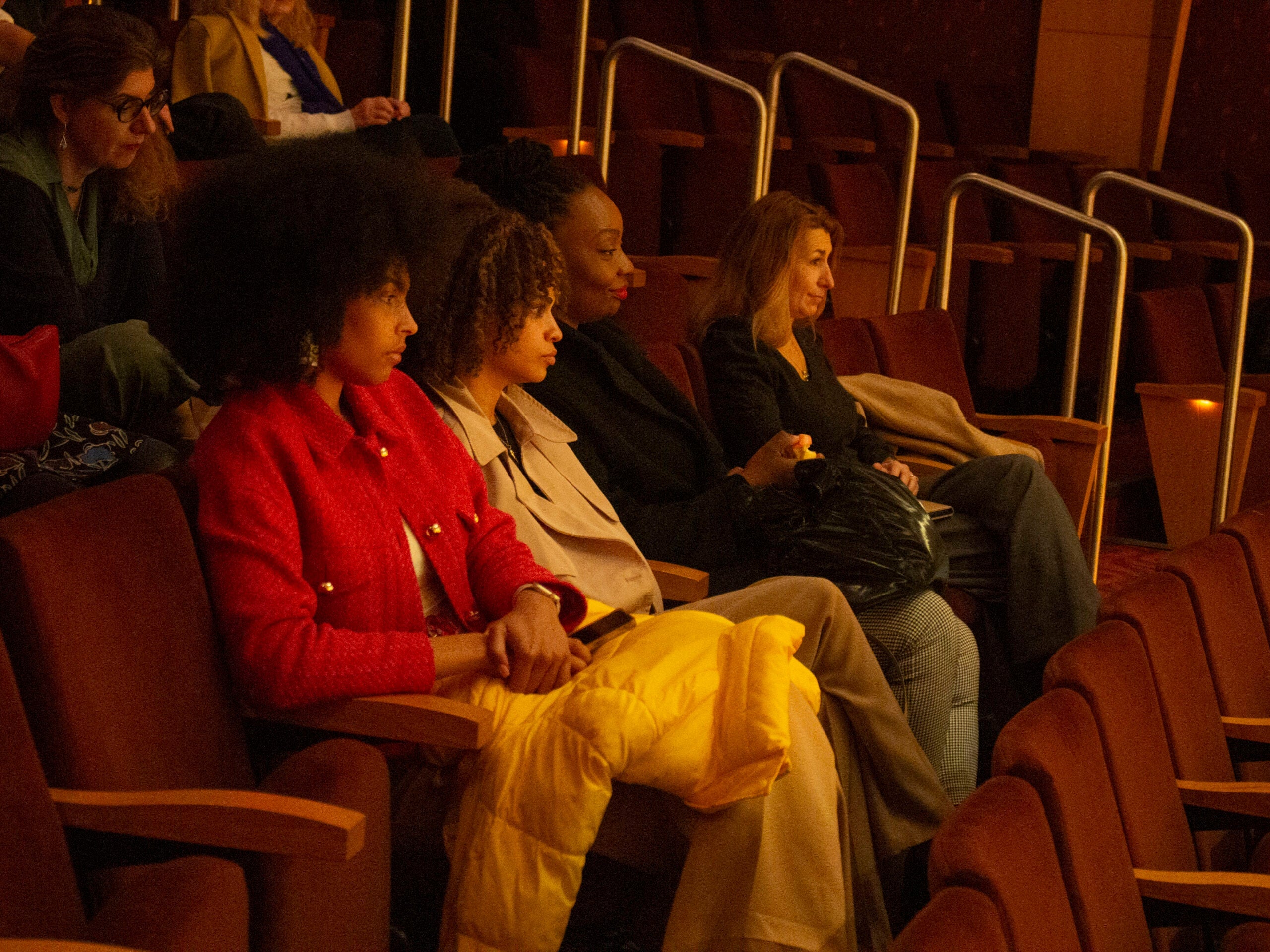 Audience members sitting in rows of chairs in an auditorium, looking forward.