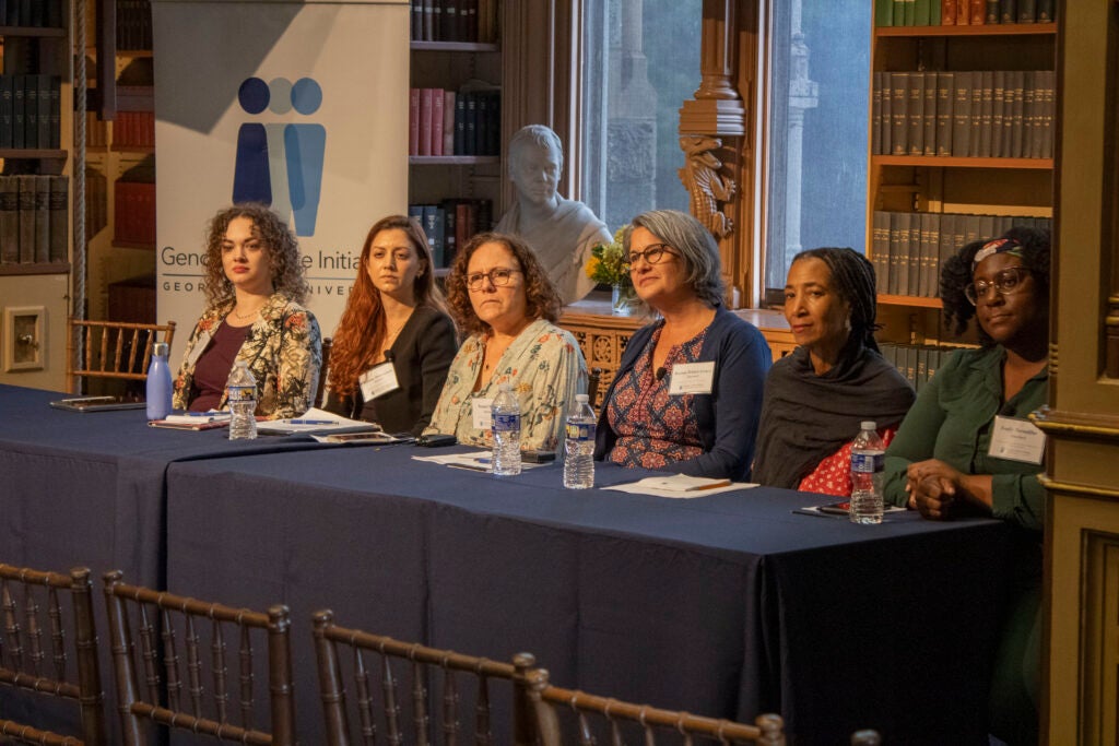 The six panelists from health justice panel are seated at a rectangular table. They are actively participating in the Q&A session.