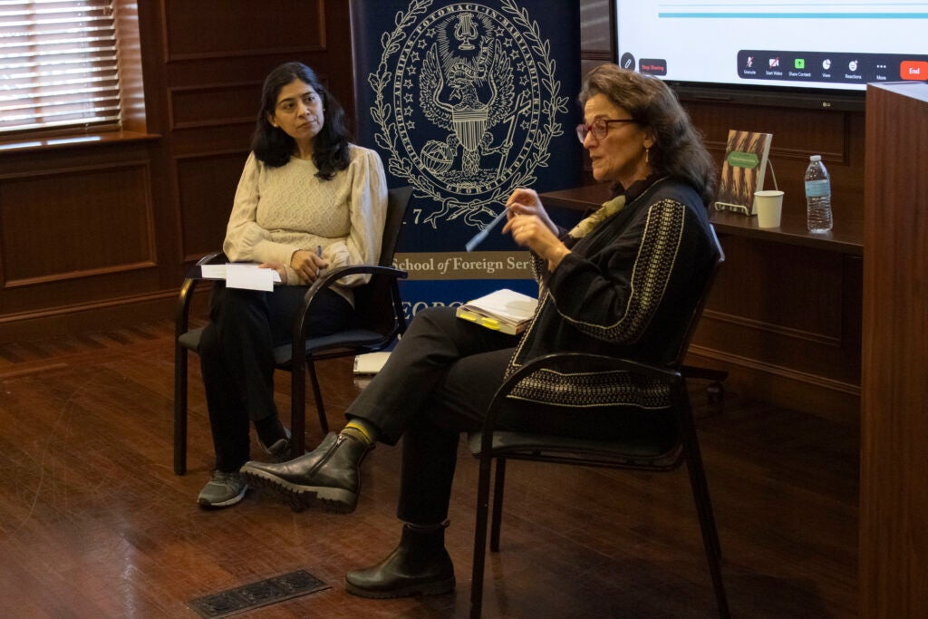 Dr. Shenila Khoja-Moolji and Dr. Fida Adely are seated in front of the projected presentation, discussing the book.