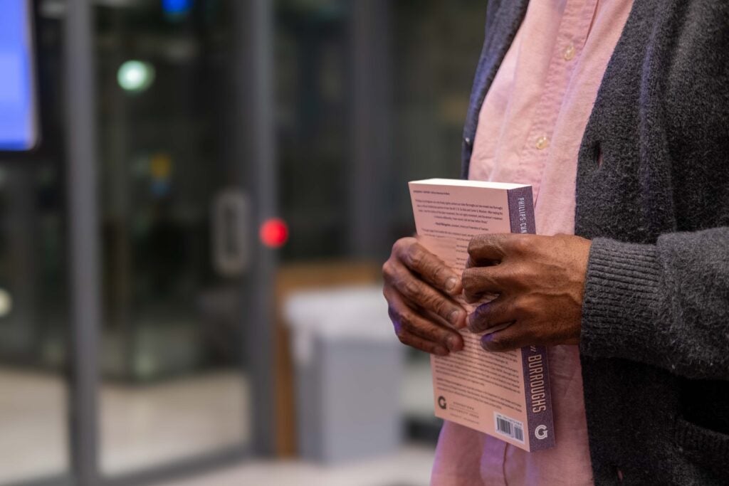 A close up photo of a pair of hands holding a paperback book titled “Nannie Helen Burroughs.” They are holding the book close to their chest. 