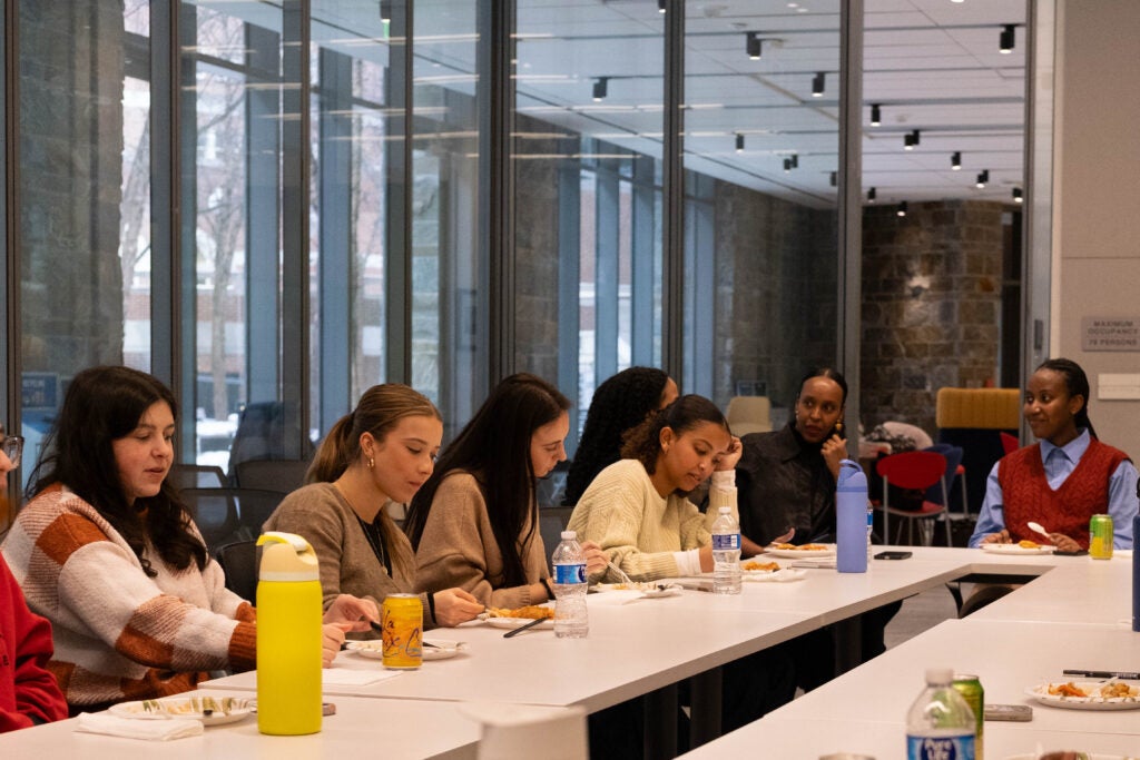 A large rectangular table of students eating with Hawa Hassan. 