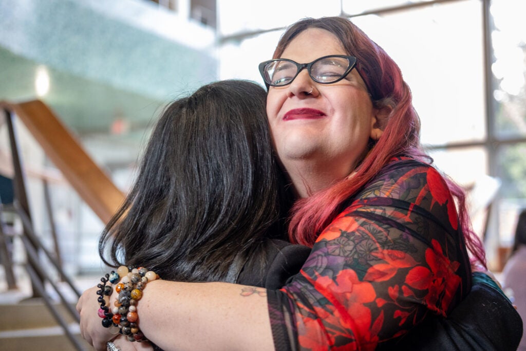 Two people hugging. The woman on the right has her eyes closed and is smiling.