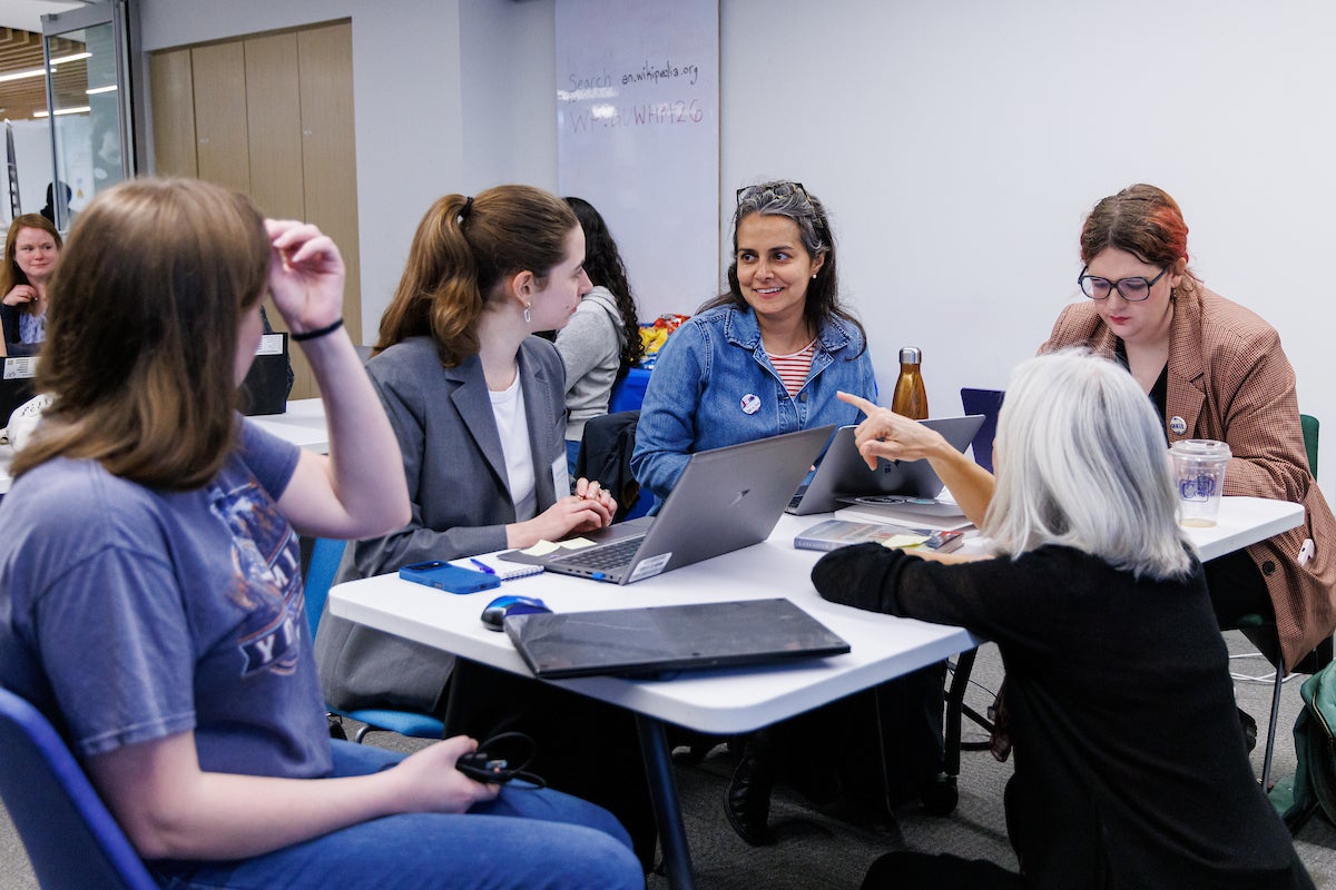 A group of people sitting around a table, working on laptop computers.