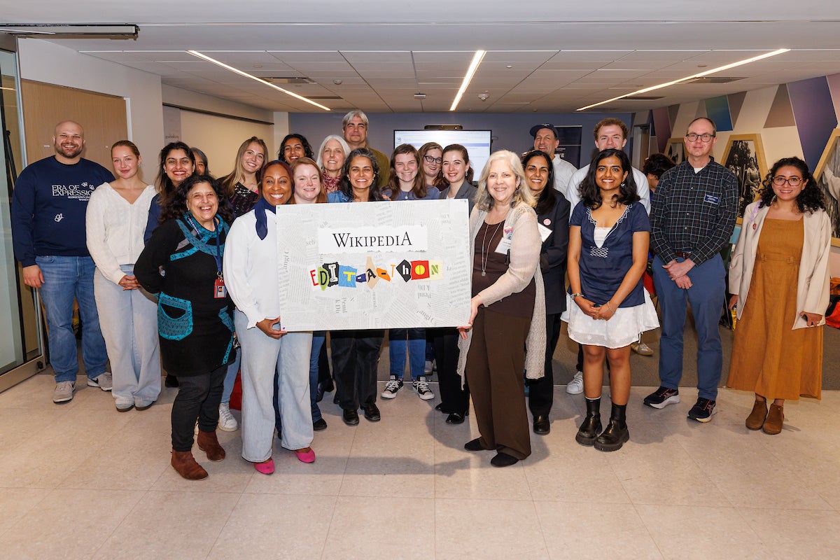 Group photo of event participants standing and smiling. The two people in front are holding a sign that reads Wikipedia Edit-a-thon 2026.