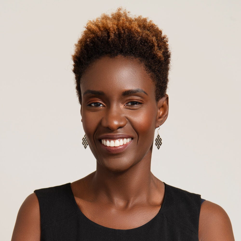 Headshot of a smiling black woman with short hair. She is wearing dangling earrings and a black blouse.